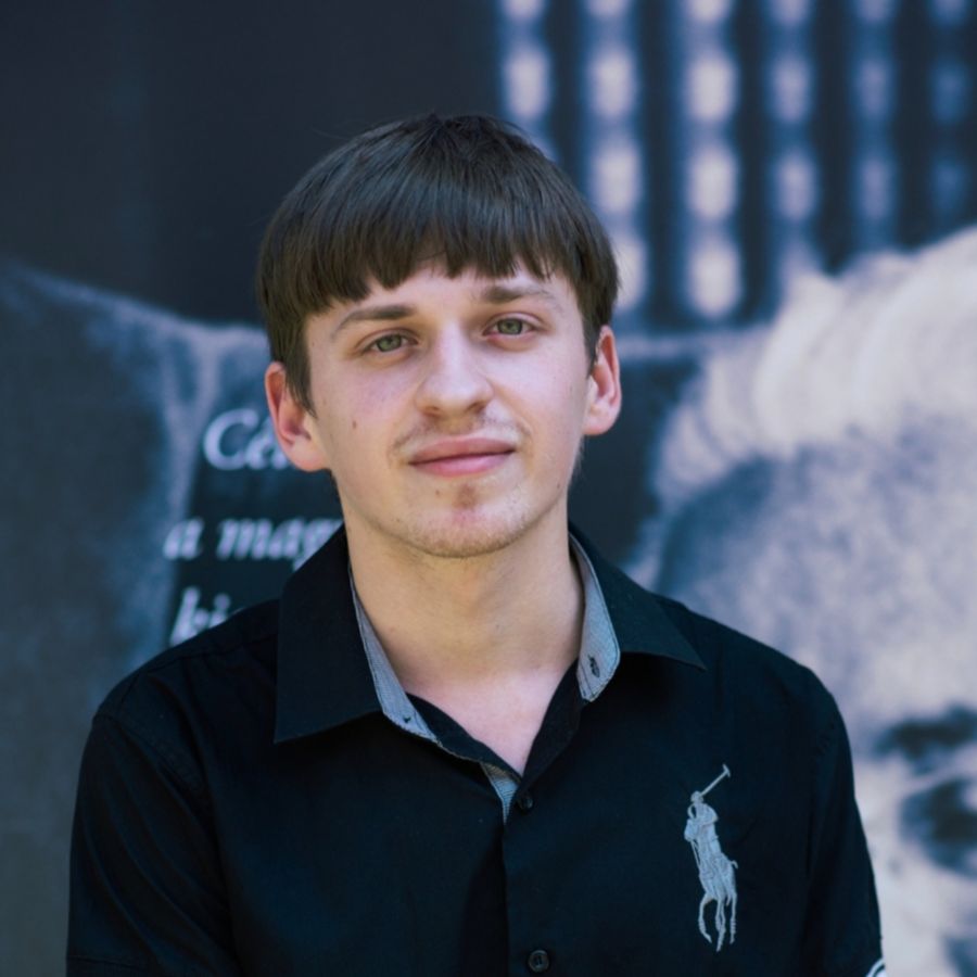 Portrait of Attila in a black shirt in front of a literary poster